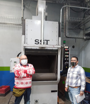 Pictured L-R: Felipe Dominguez (Tooling Department Manager), Christofer Palacios (Process Engineer) in front of a Tumblast Machine